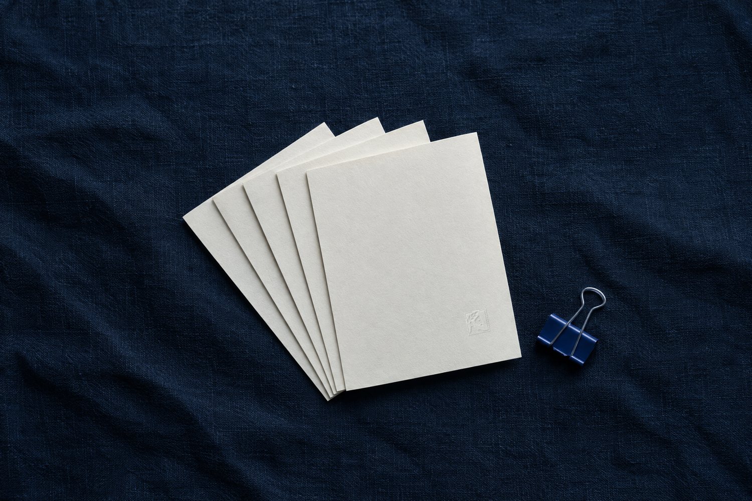 Five blank cream index cards fanned out with a blue binder clip, the Olivent mark embossed on the top card