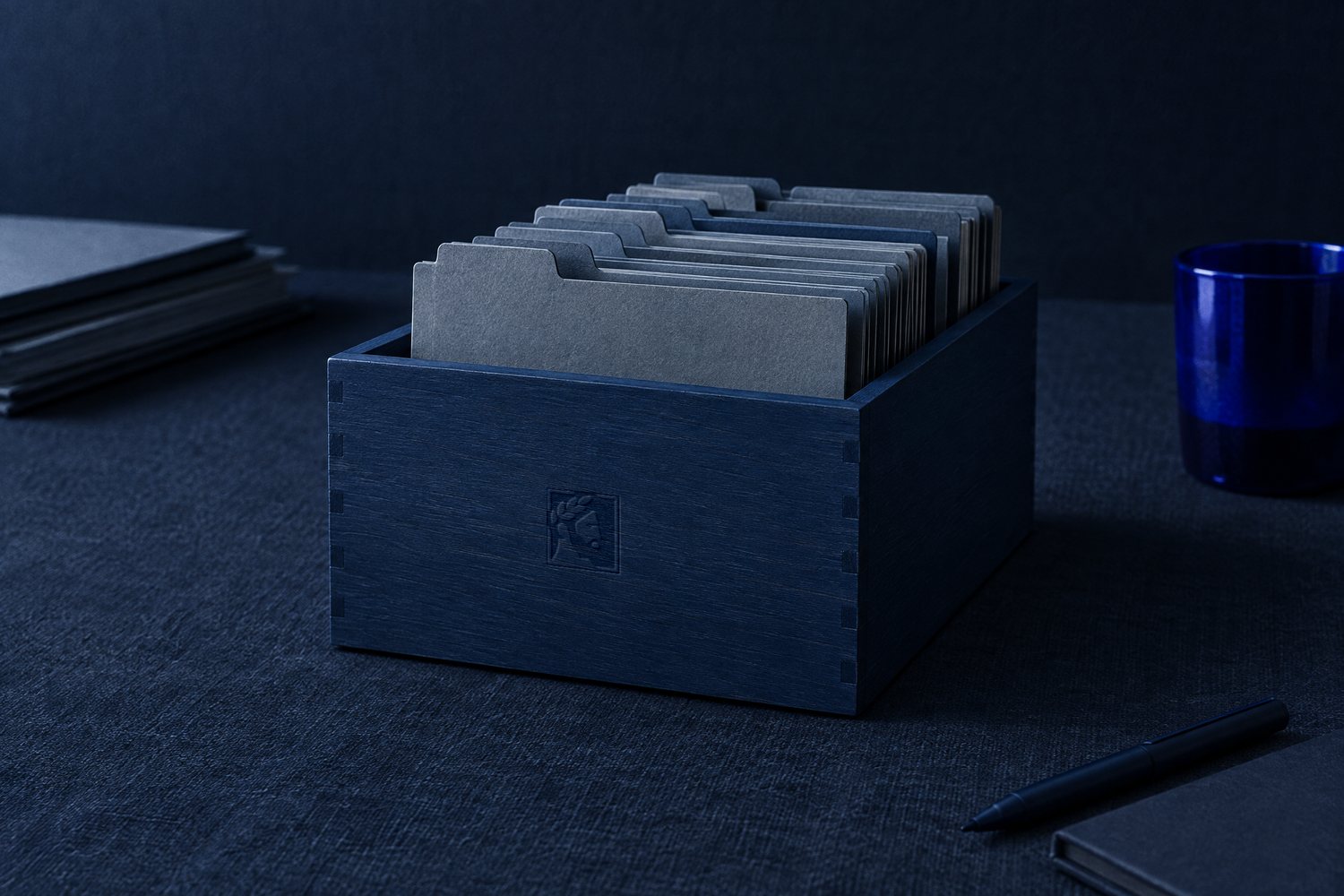 A navy wooden index-card box full of slate dividers, the Olivent mark pressed into its front