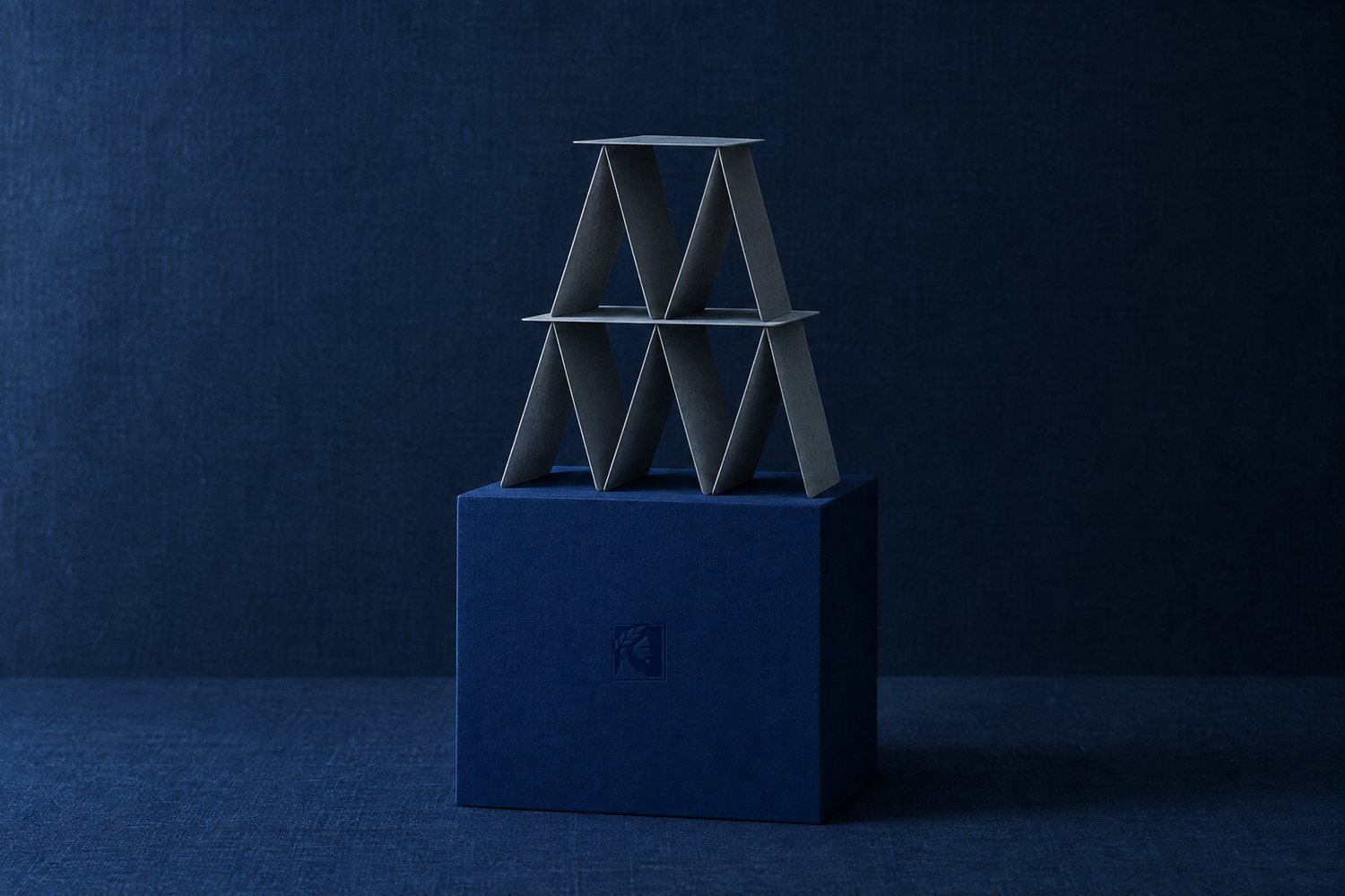 A house of blank grey cards standing on a navy plinth pressed with the Olivent mark