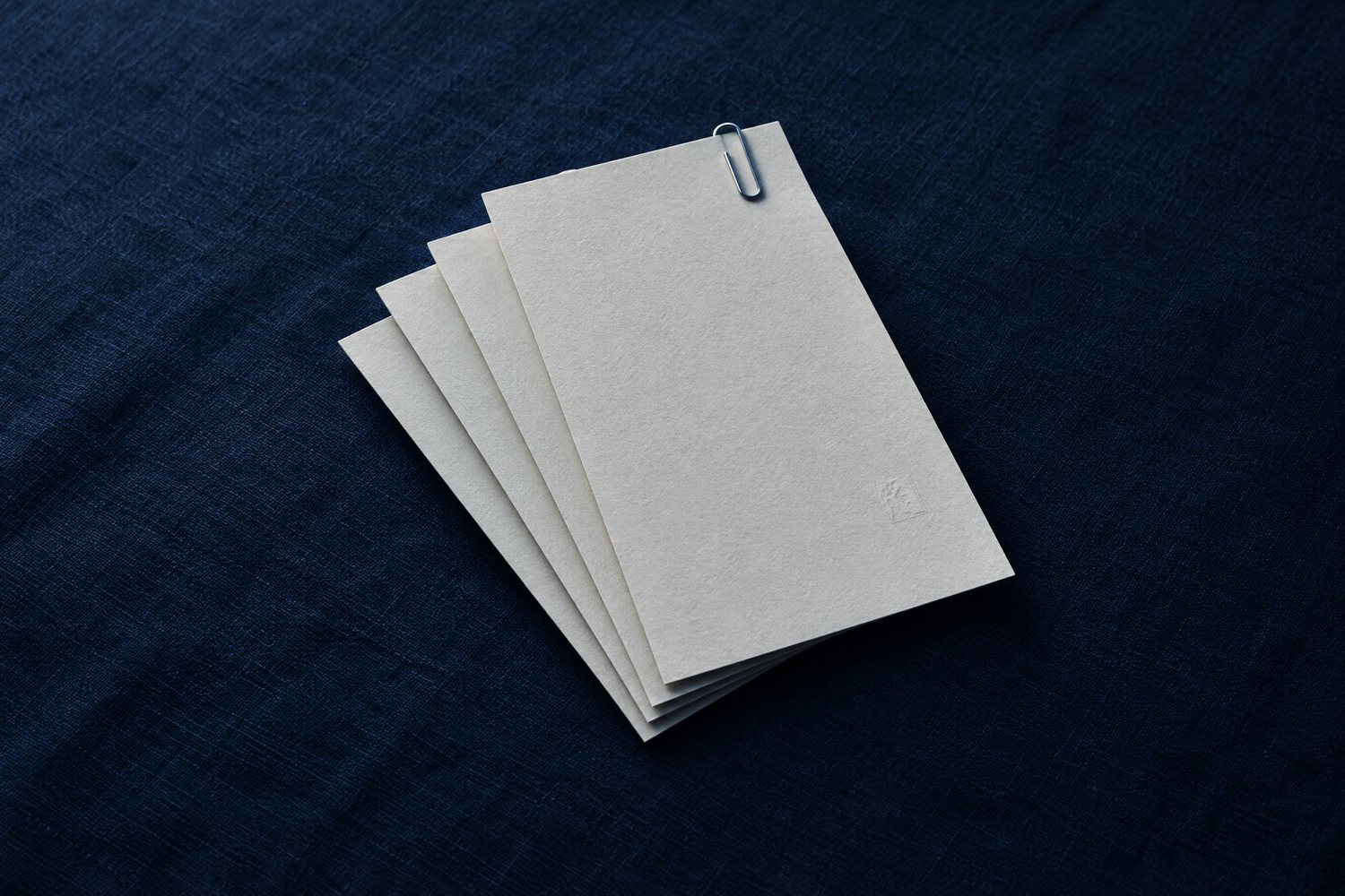 Four sheets of cream paper fanned out with a steel paperclip, the top sheet embossed with the Olivent mark