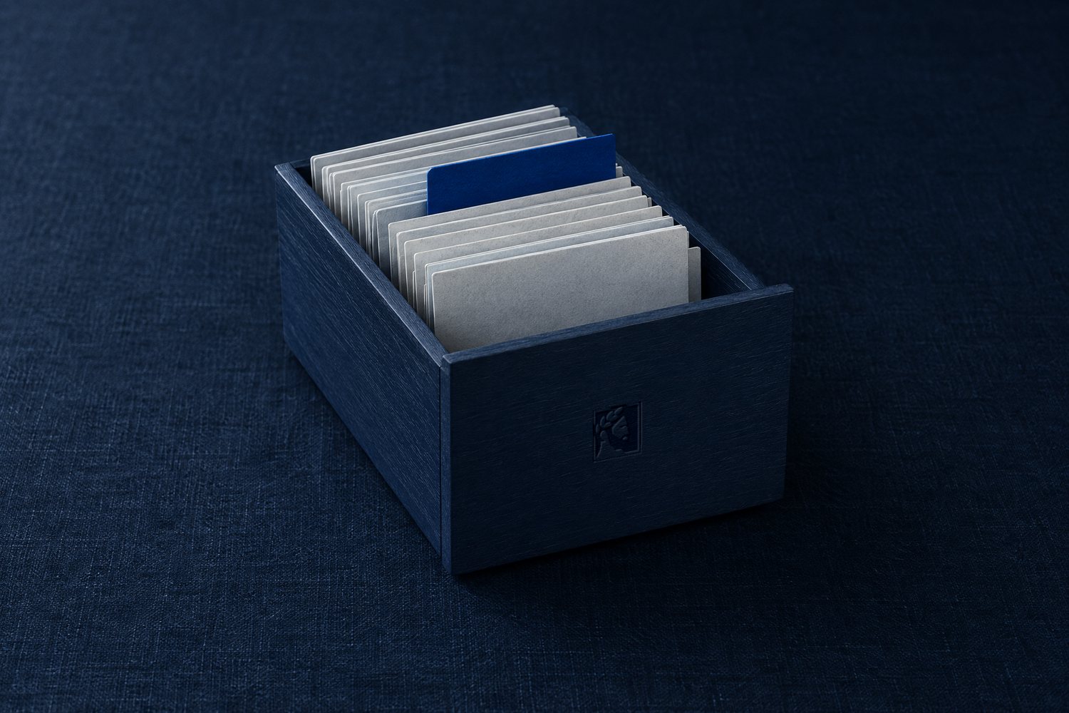 A navy wooden card-file box of blank index cards with one cobalt divider, the Olivent mark on its front