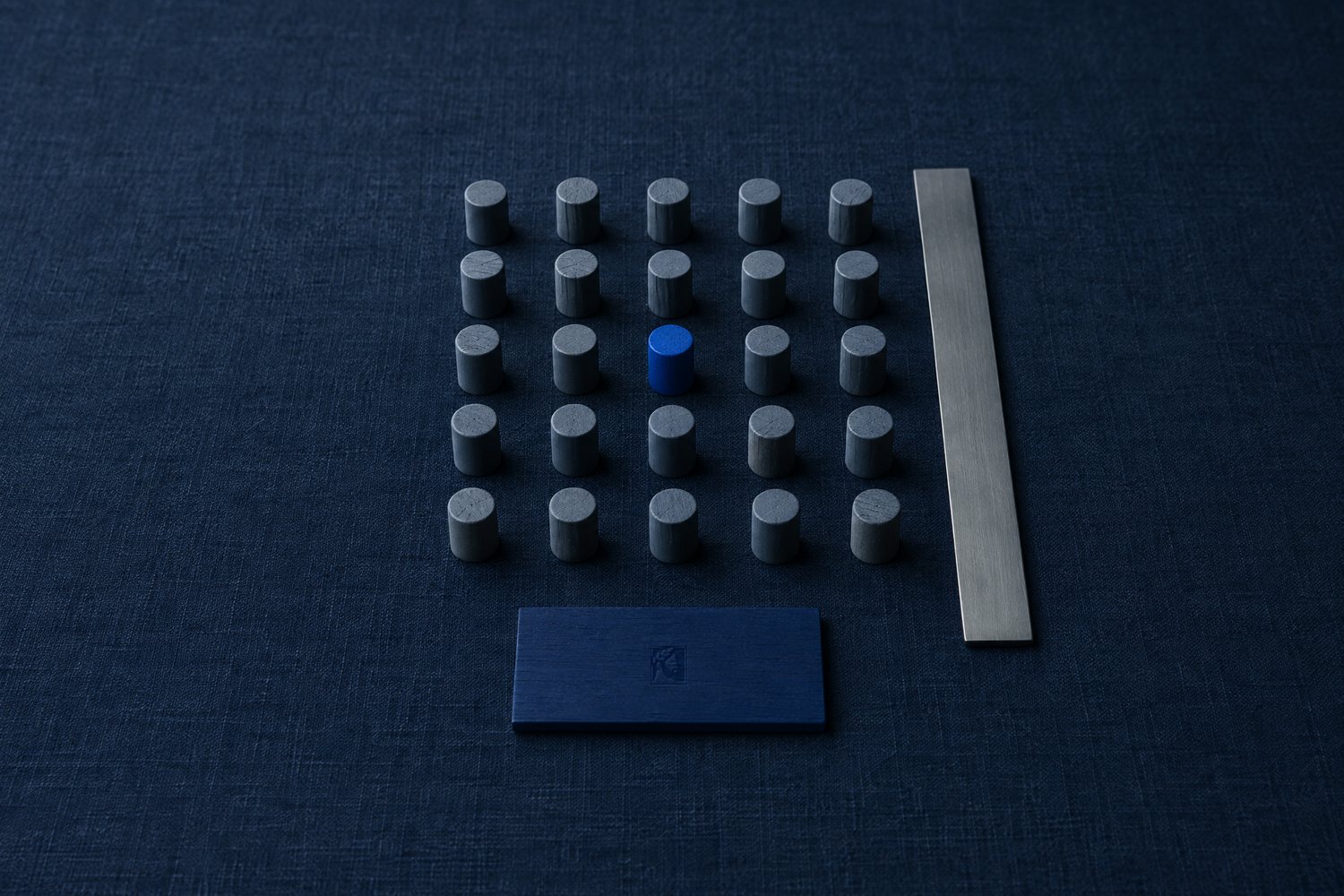 A grid of slate pegs with one cobalt peg, a plain steel ruler beside them and a navy plaque stamped with the Olivent mark