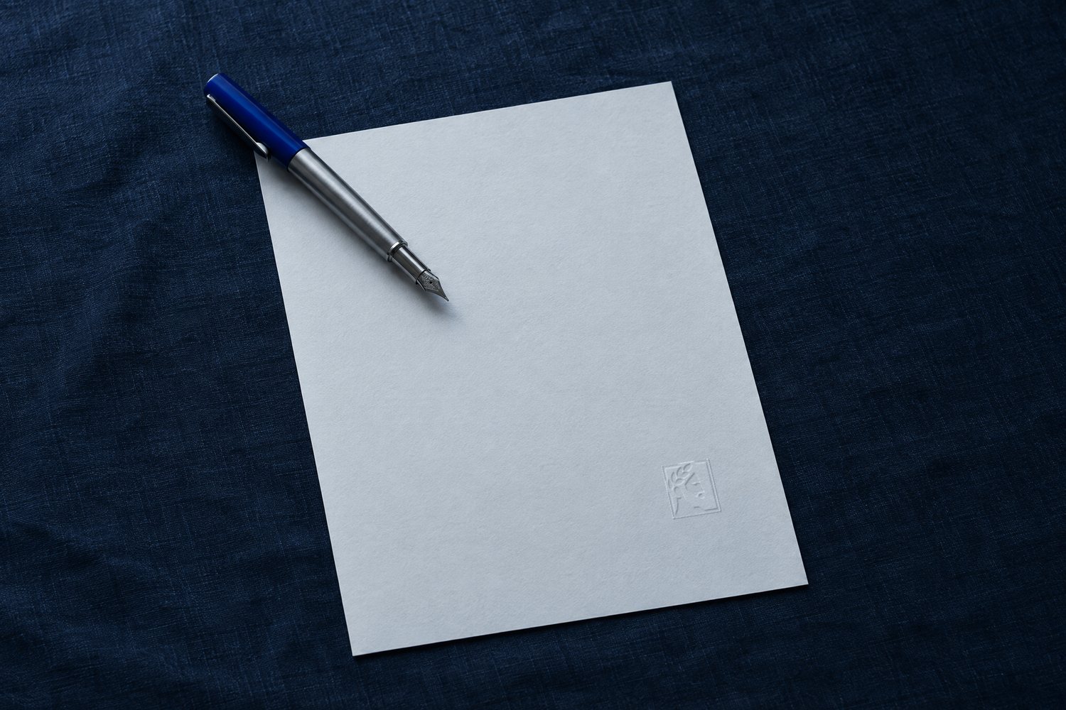 A single blank sheet with a steel fountain pen across one corner, the Olivent mark embossed at the bottom right