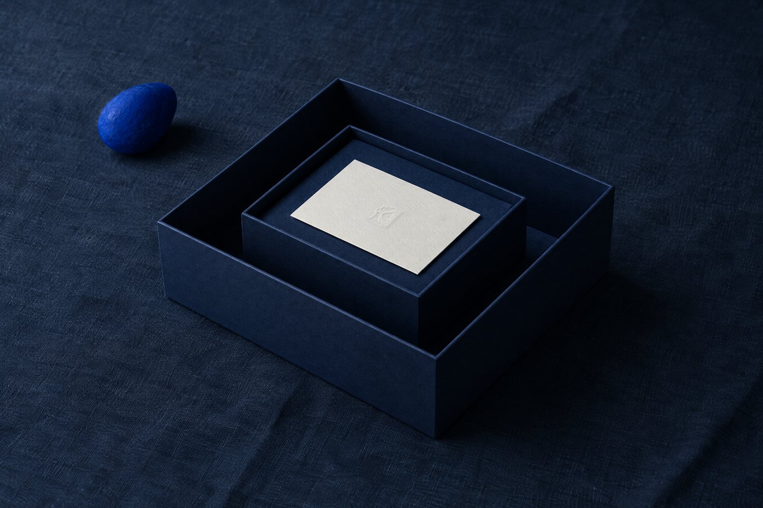 A small navy box nested inside a larger one, a card with the Olivent mark inside the smaller box