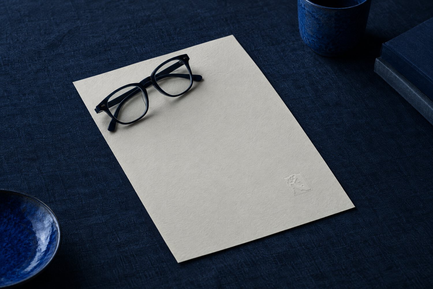 Reading glasses on a sheet of cream paper embossed with the Olivent mark