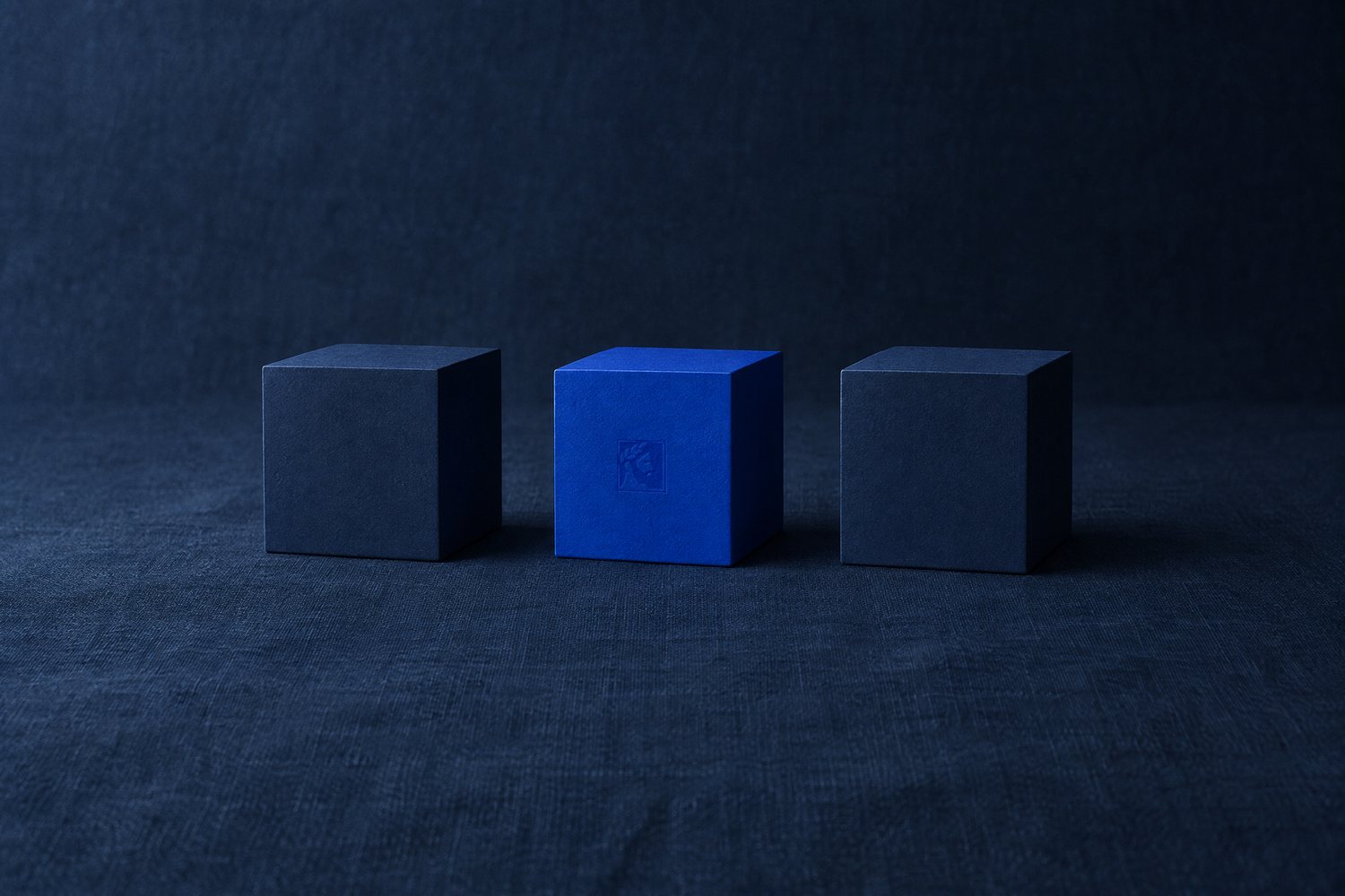 Three navy cubes in a row, the middle one cobalt, with the Olivent mark pressed into its face
