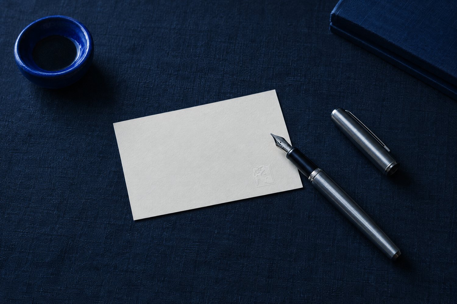 An off-white card embossed with the Olivent mark next to an uncapped steel fountain pen