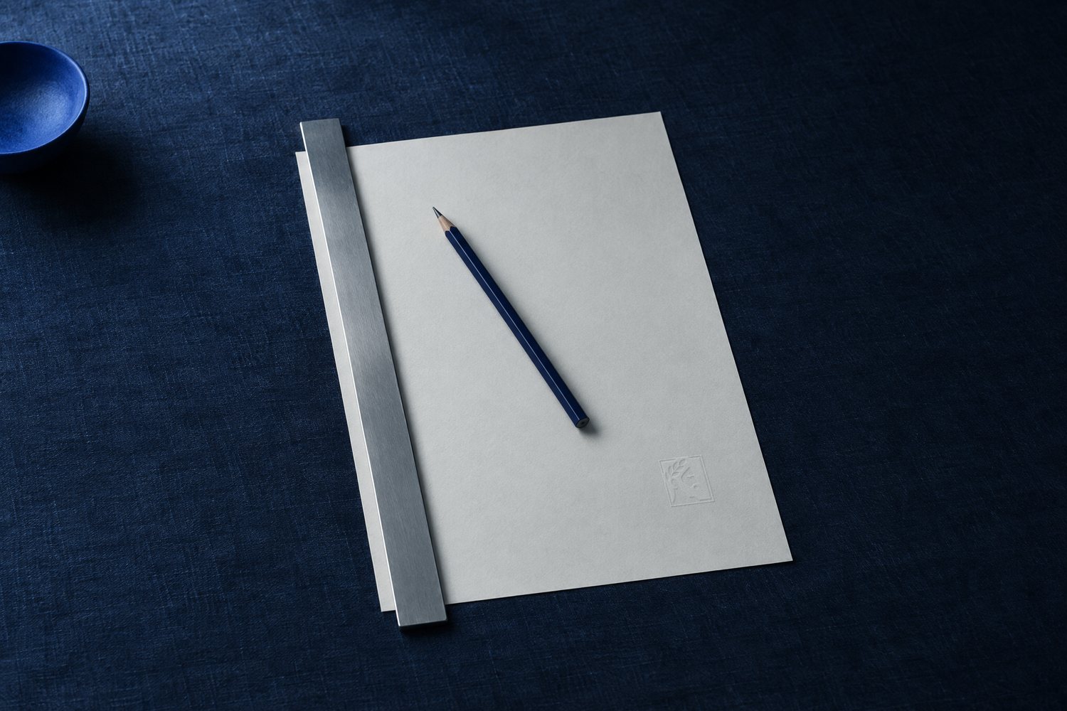 A sheet of off-white paper embossed with the Olivent mark, a steel straightedge along its edge and a pencil