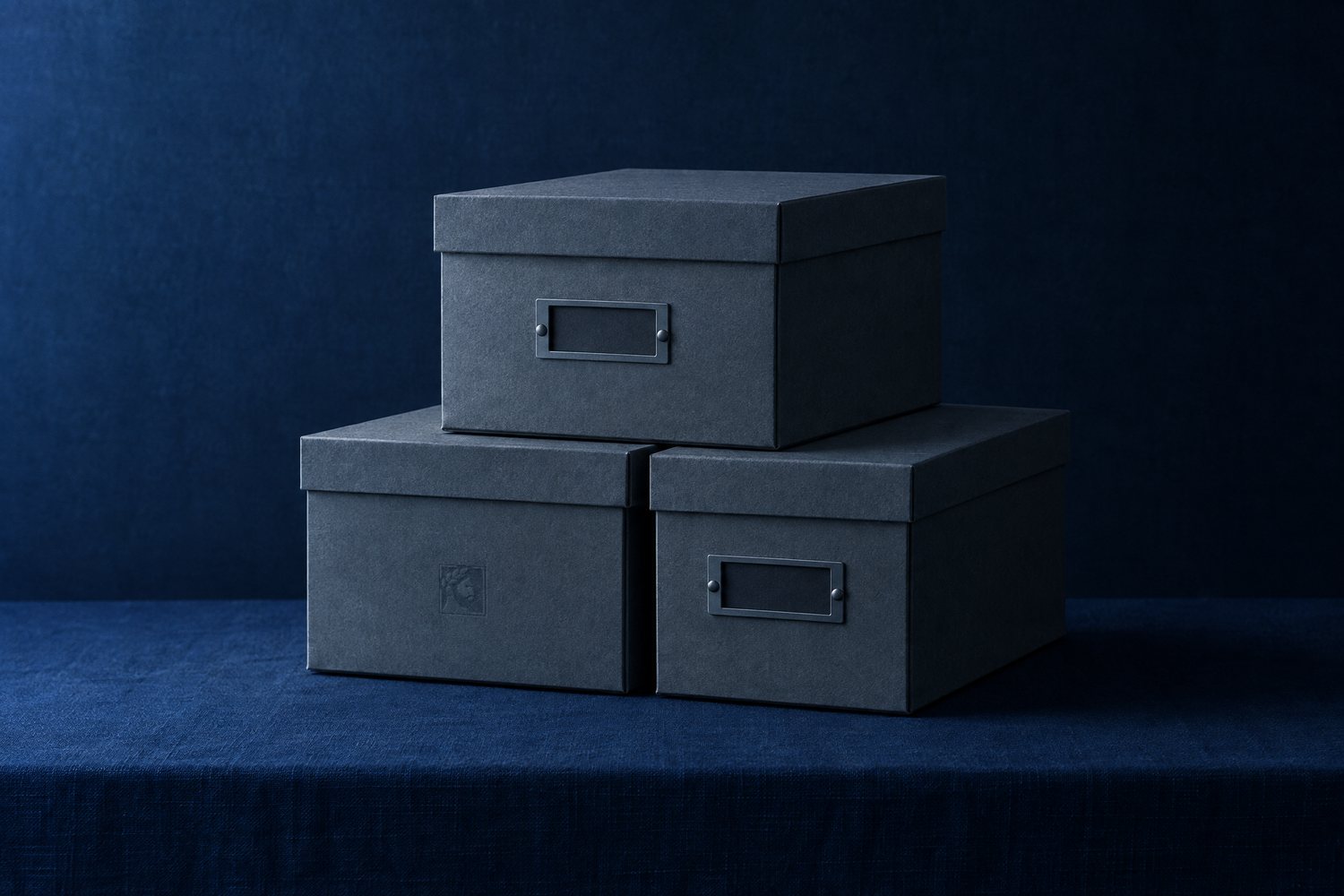 Three stacked slate grey archive boxes, the lower left one debossed with the Olivent mark